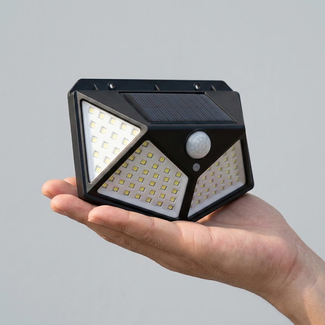 Luminária solar de parede com 100 LEDs para muro, quintal e garagem em uso, mostrando o tamanho real