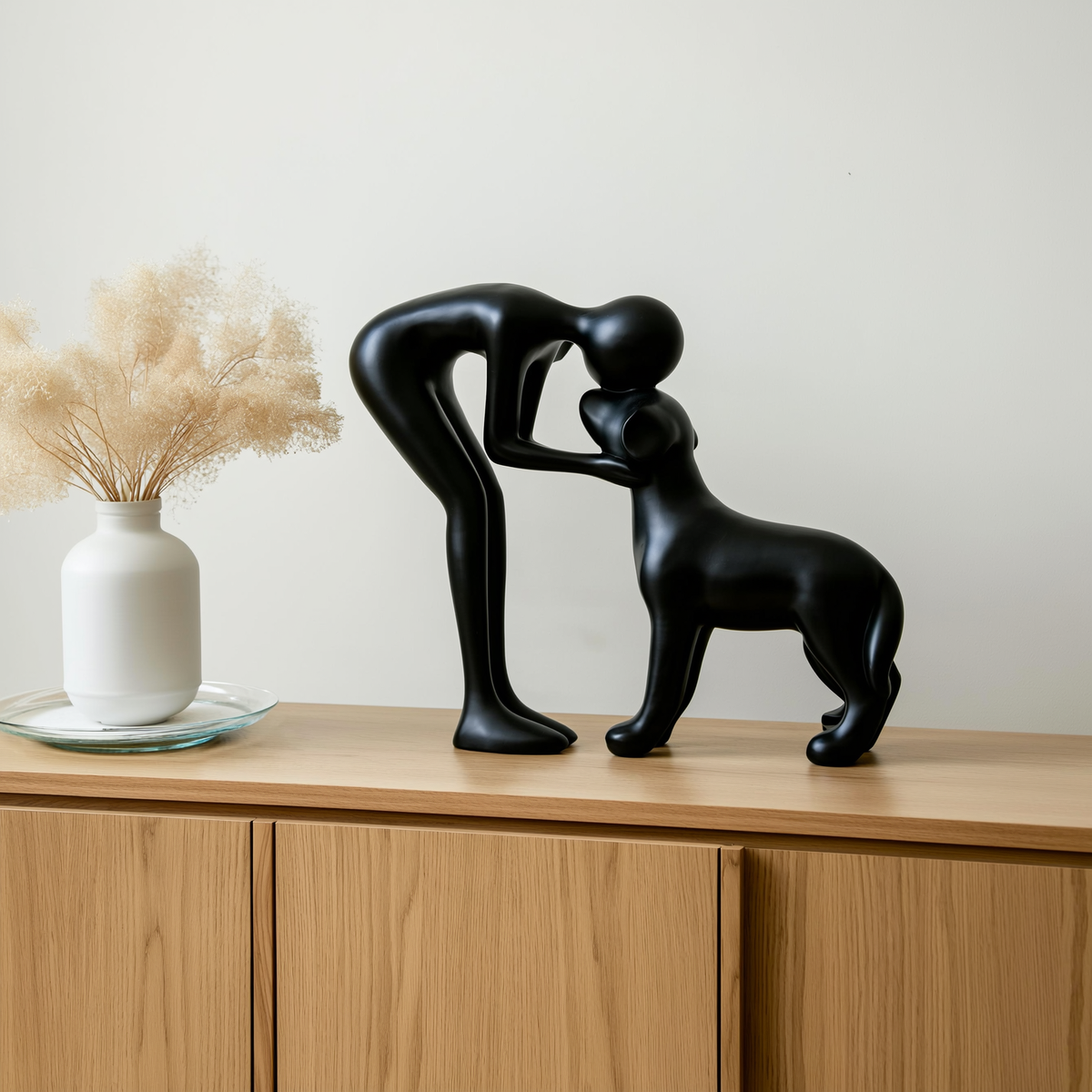 Escultura abstrata de homem e cachorro em resina preta sobre aparador de madeira clara — foto de ambiente 2