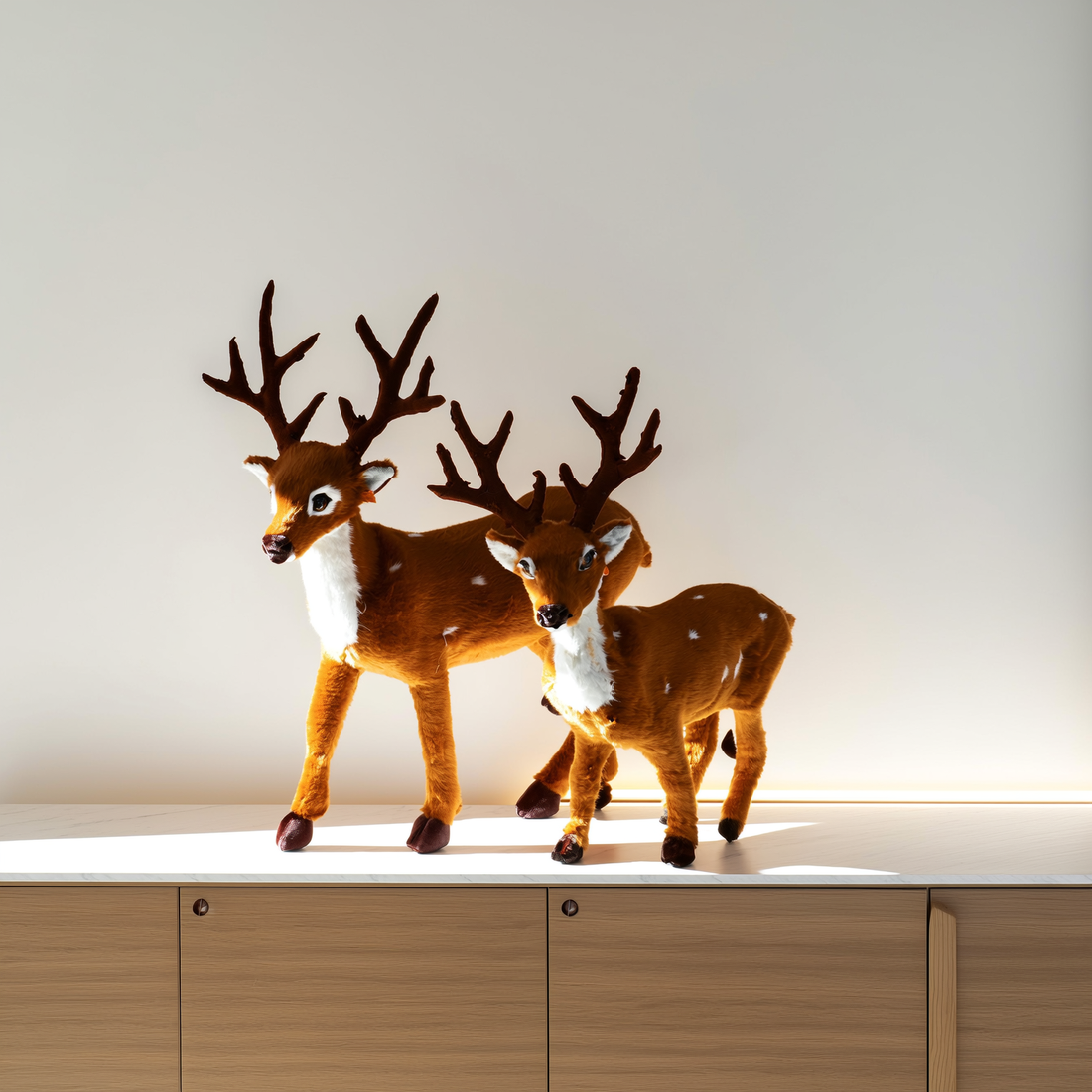 Renas de pelúcia de Natal em dois tamanhos sobre aparador claro — foto de ambiente 2