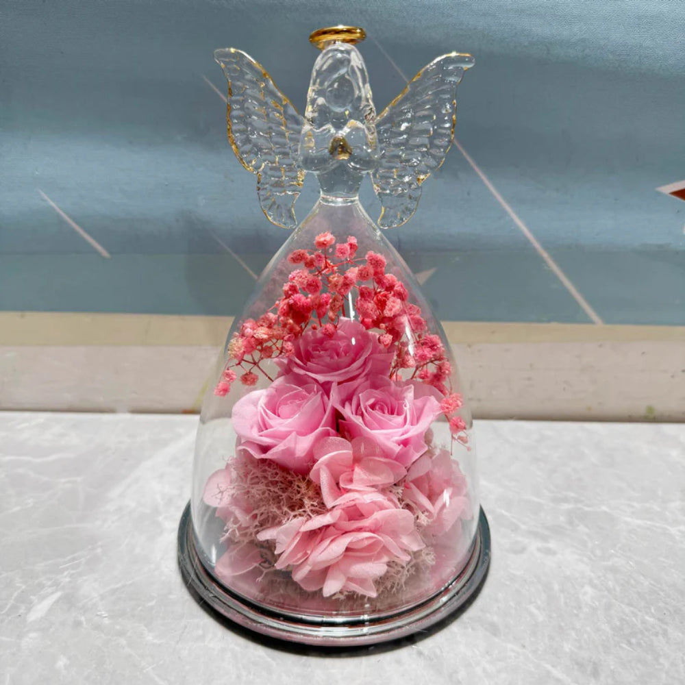 Redoma de vidro com rosa preservada e figura de anjo, com luzes de LED acesas