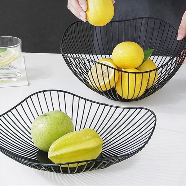 Fruteira aramada de metal preta com frutas sobre a bancada da cozinha