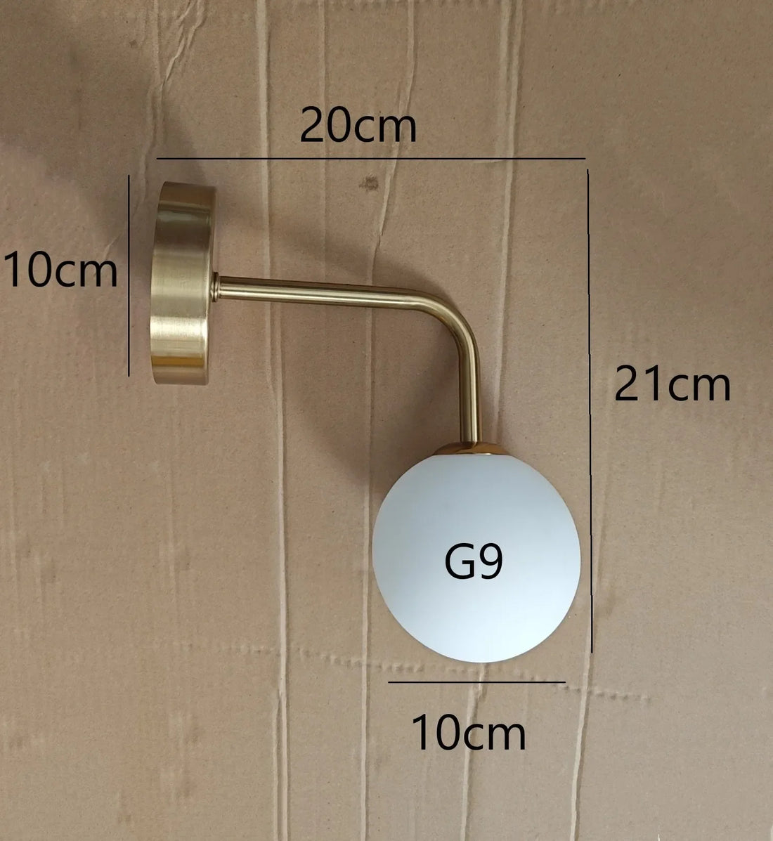 Arandela dourada com cúpula de vidro acesa na parede do quarto