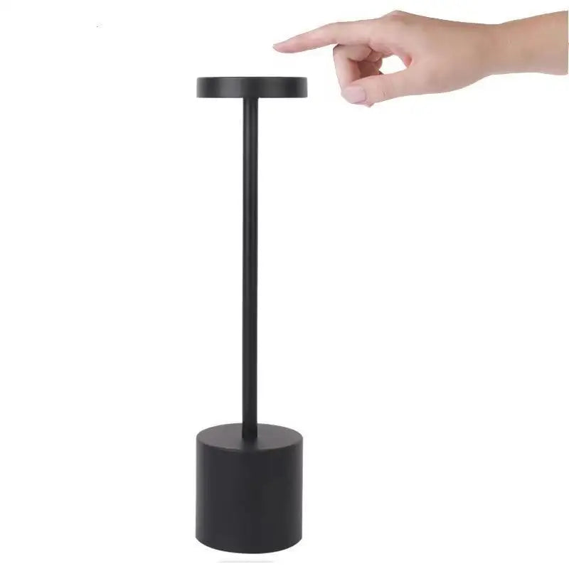 Luminária de mesa recarregável preta acesa sobre o criado-mudo