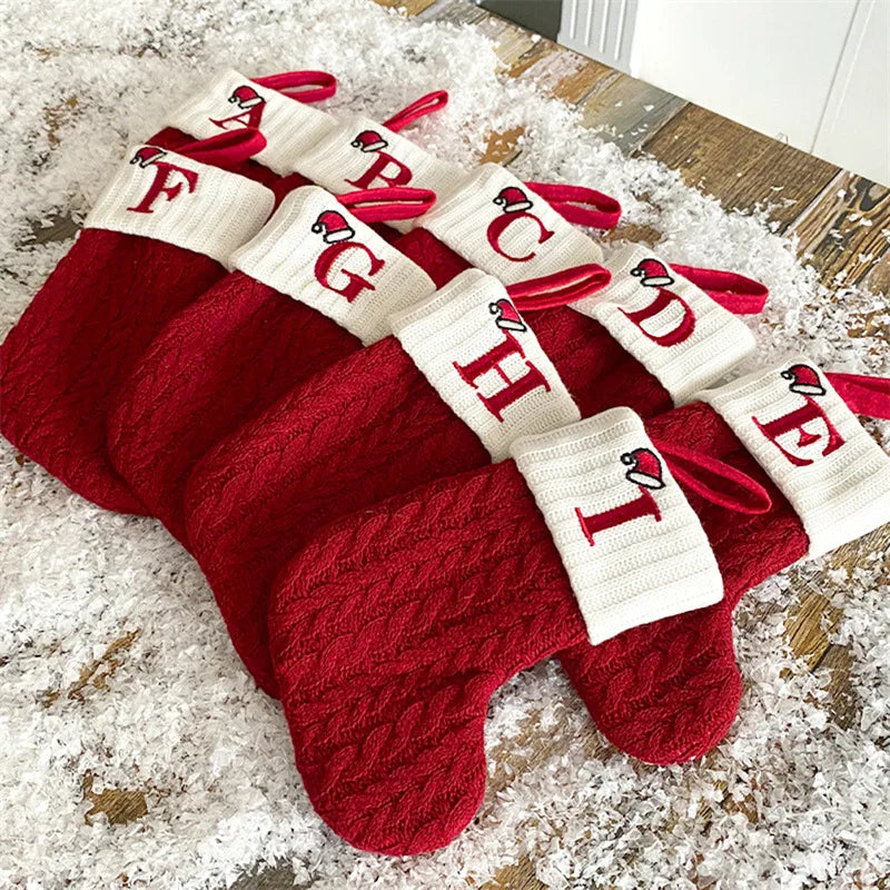 Meia de natal de tricô com letra do alfabeto pendurada na estante decorada
