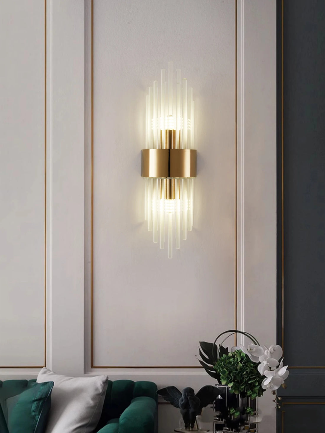 Arandela de cristal com base dourada acesa na parede da sala