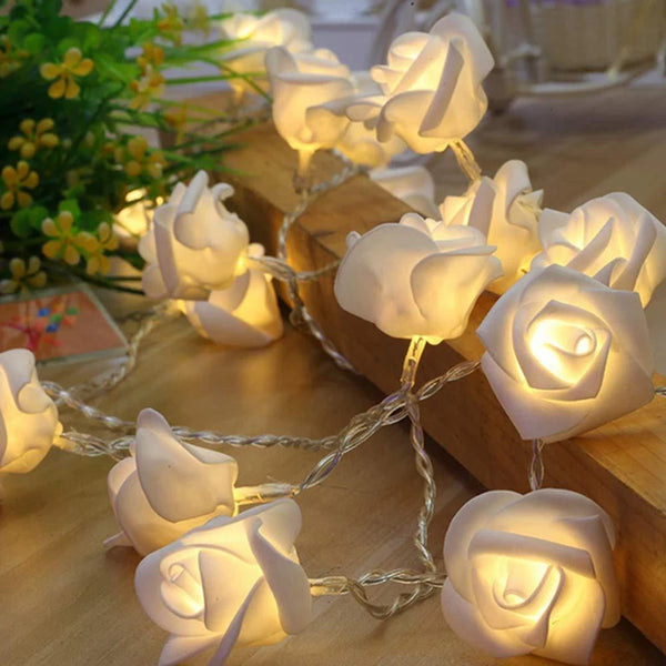 Cordão de luz com flores de rosa branca aceso sobre uma cabeceira