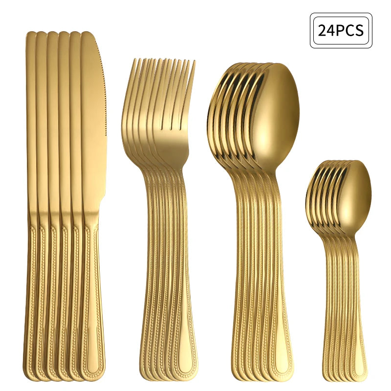 Faqueiro dourado de aço inox disposto sobre uma toalha clara ao lado de um prato branco