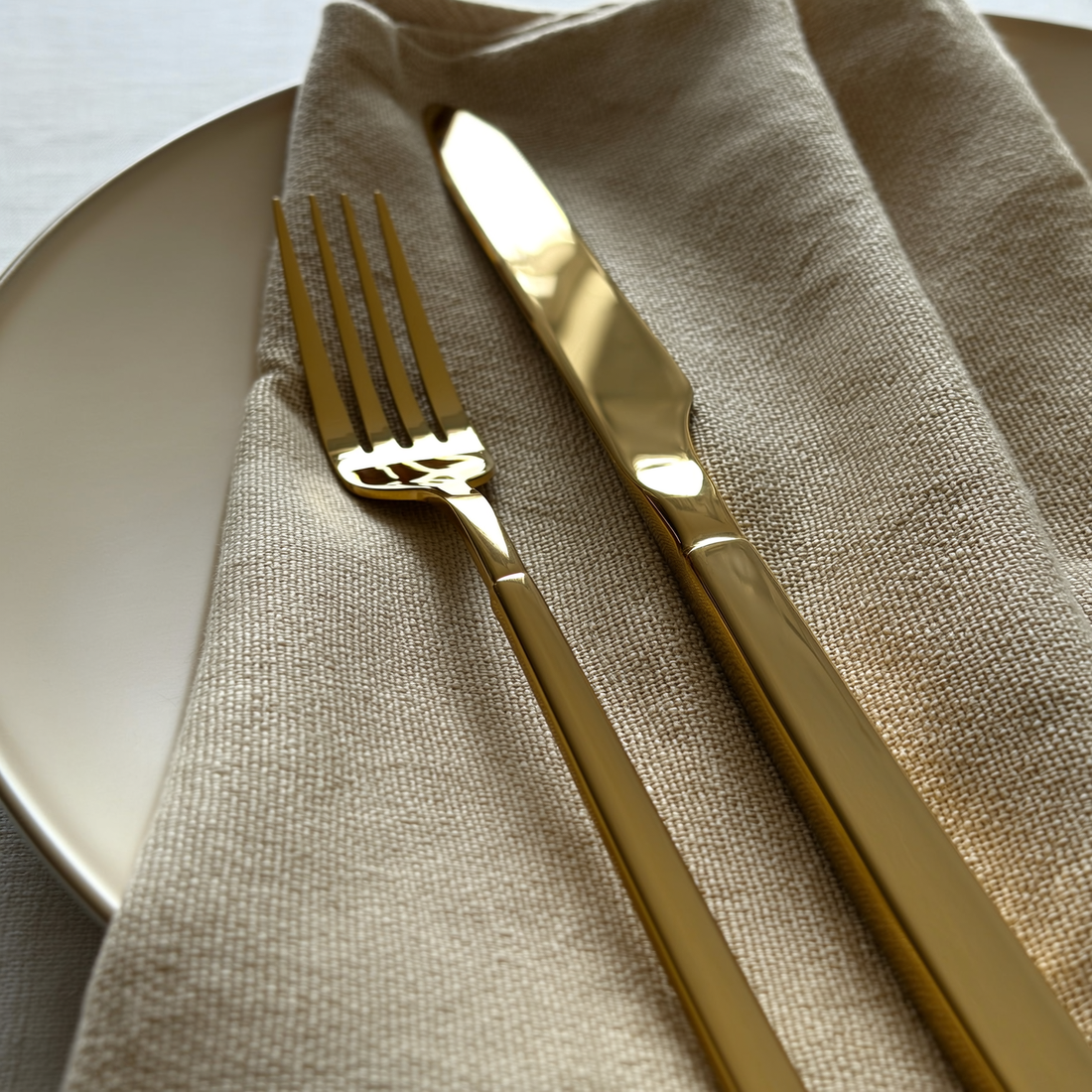Kit de talheres dourado em mesa de jantar posta com guardanapo de linho — foto de ambiente 1