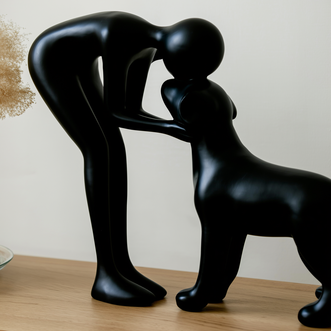 Escultura abstrata de homem e cachorro em resina preta sobre aparador de madeira clara — foto de ambiente 3