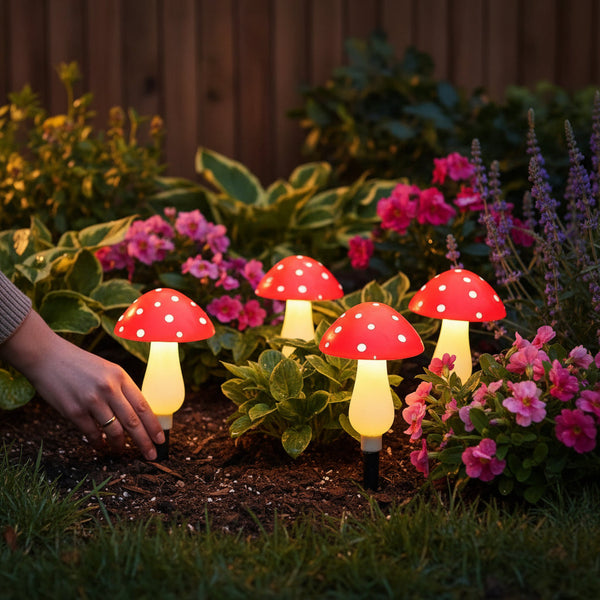 Luminárias solares em formato de cogumelo acesas espetadas em um canteiro de jardim